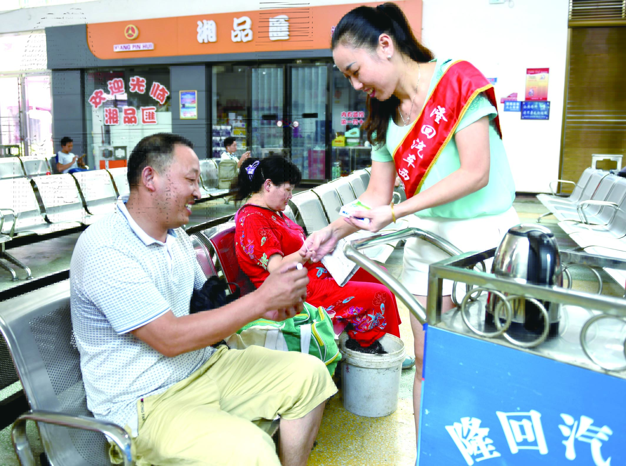 隆回分公司汽車西站工作人員正在為旅客免費贈送藿香正氣水。